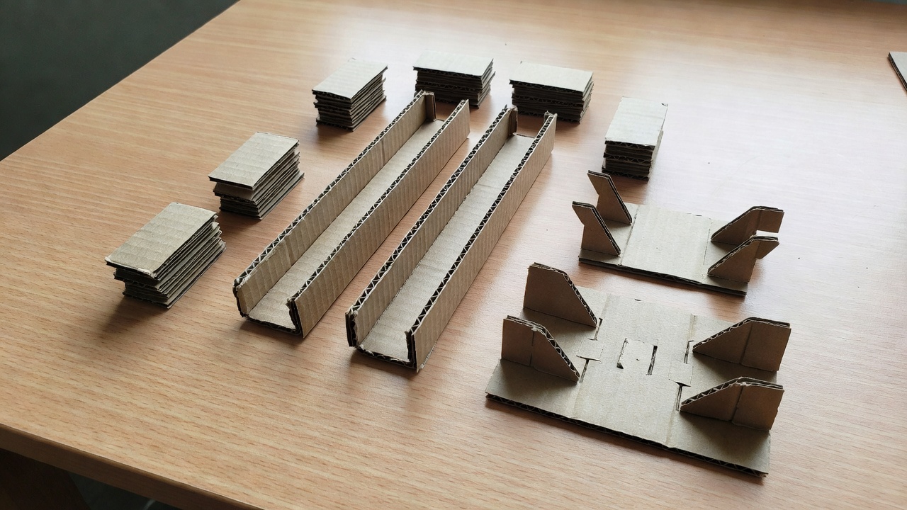 Two short cardboard channels and separate support blocks arranged before assembly on a desk